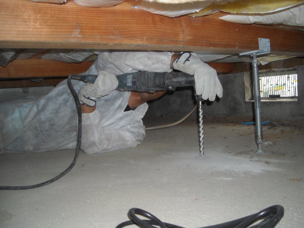 住宅の床下でJOG工法の注入管を設置する現場施工スタッフ